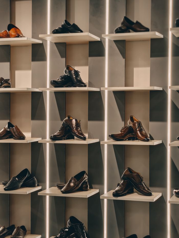 who-we-are A stylish display of brown men's dress shoes organized neatly on modern shelves in a store.