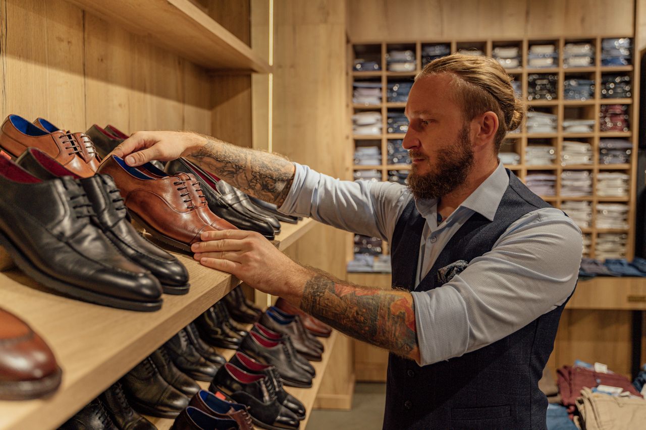 services-03 Caucasian man browsing leather shoes in a stylish clothing store. Adult male in trendy fashion setting.